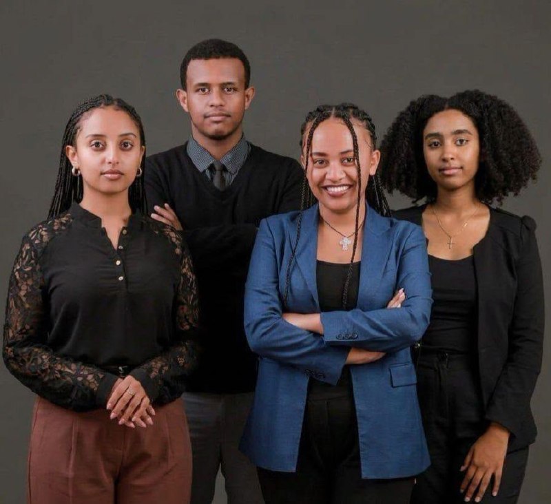 Four Addis Ababa University law students standing together against a dark grey studio backdrop, three women and one man in formal black and blue clothing.