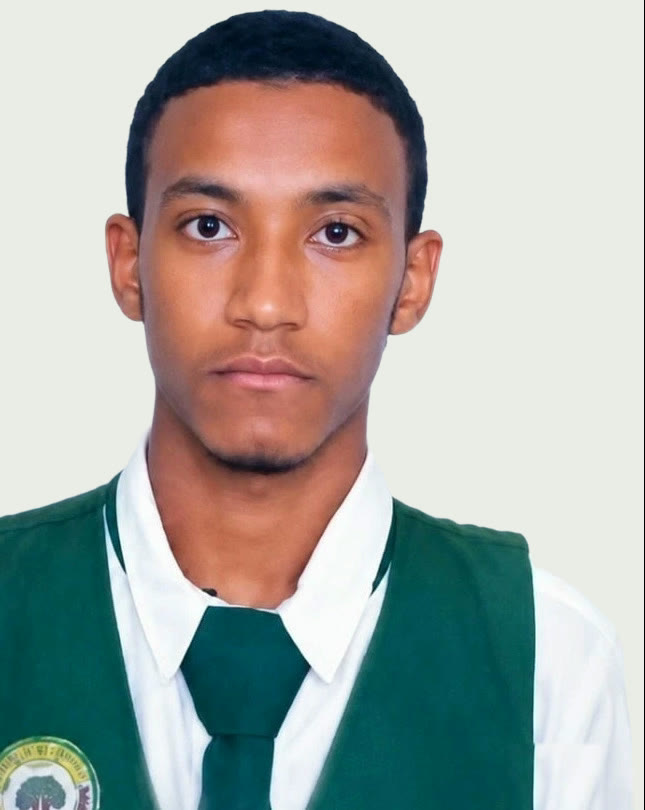 Jalal Girma facing the camera in his school uniform, a dark green sleeveless pullover with the school crest on the chest, worn over a white shirt and a green tie.